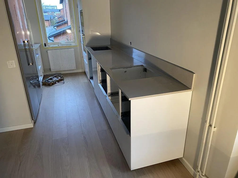 Køkkenbordplade i Technistone Noble Ivory White, poleret kvartskomposit, längs en lige köksrad med låg stänkkant i Helsingborg.