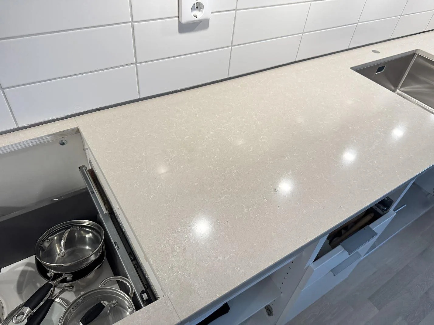 Køkkenbordplade i Technistone Noble Ivory White, poleret kvartskomposit, med hällurtag og underlimmad rostfri vask i ett køkken i Landskrona.