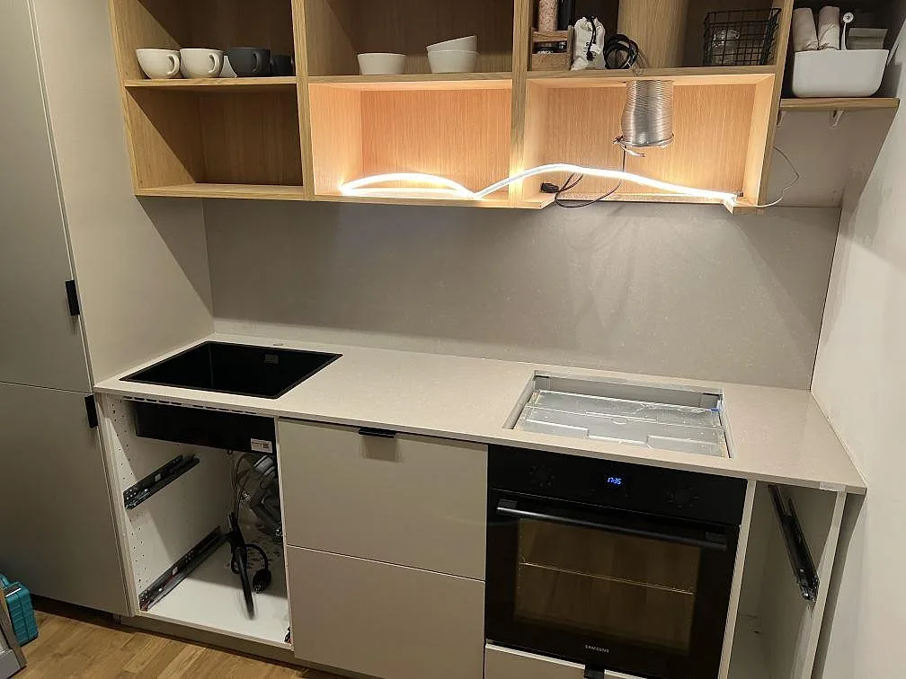 Køkkenbordplade i poleret Technistone Noble Ivory White kvartskomposit med sort kogeplade og diskhoområde under montering i ett køkken i Stockholm.