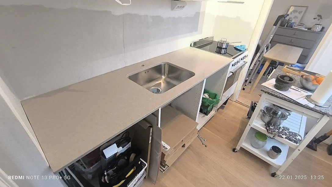 Køkkenbordplade i 20 mm poleret Technistone Noble Ivory White, lys kvartskomposit med rostfri vask i ett køkken under montering i Stockholm.