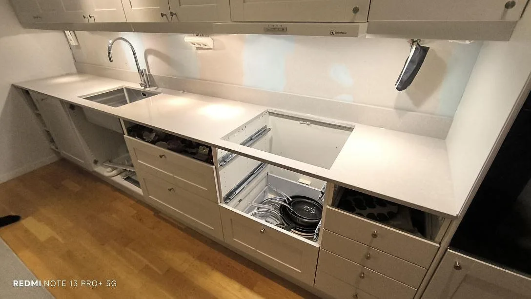 Køkkenbordplade i lys Technistone Noble Ivory White kvartskomposit, poleret, med underlimmad vask og hälluttag under montering i Uppsala.