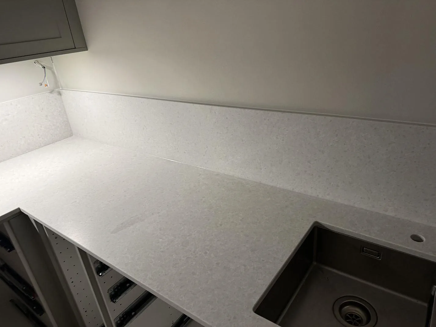 Køkkenbordplade i ljusgrå Technistone Noble Quartzite, kvartskomposit med blandad mat og poleret finish, med rostfri vask og stænkplade i ett køkken i Malmö.