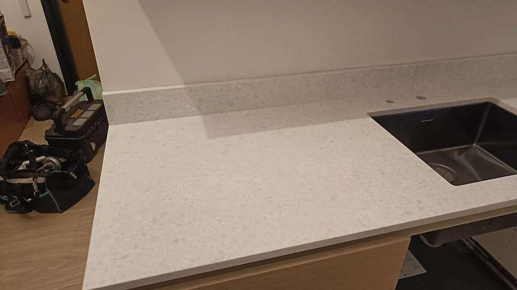 Køkkenbordplade i mat Technistone Noble Quartzite med låg stänkkant og monteret vask i ett køkken i Malmö.
