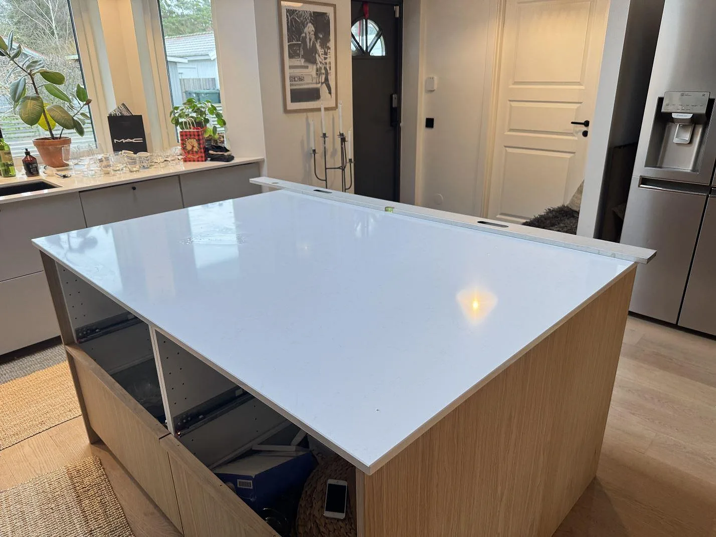 Køkkenø i 20 mm poleret Technistone Noble Supreme White komposit med lys sten og öppna lådpartier i ett køkken i Höllviken.
