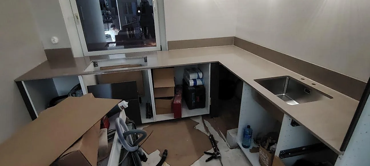 Køkkenbordplade i 20 mm Technistone Noble Troya, poleret kvartskomposit, med uppvikt stänkkant i ett køkken under montering i Solna.