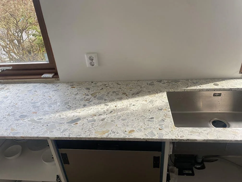 Køkkenbordplade i hvid Terrazzo Calacatta med krossad marmor, mat overflade, og underlimmad rostfri vask i ett køkken i Bjärred.
