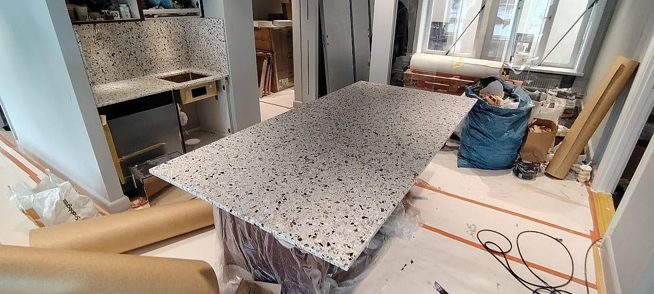 Mat køkkenbordplade i Terrazzo GV med stor arbetsyta og matchande stænkplade under montering i Stockholm.
