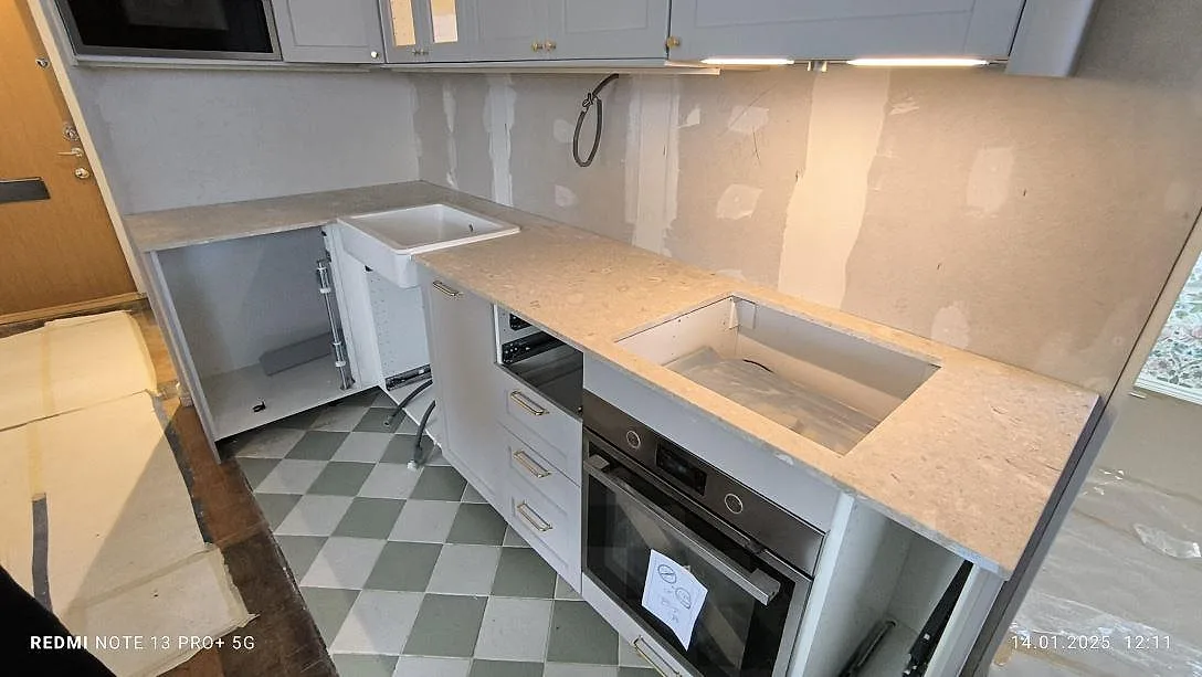 Mat køkkenbordplade i beige Terrazzo Perlato Royal på en lang bänkrad i ett køkken under montering i Lidingö.