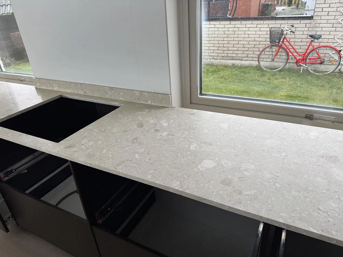 Køkkenbordplade i mat Terrazzo Perlato Royal med låg stänkkant og rektangulär öppning vid vindue i Löddeköpinge.