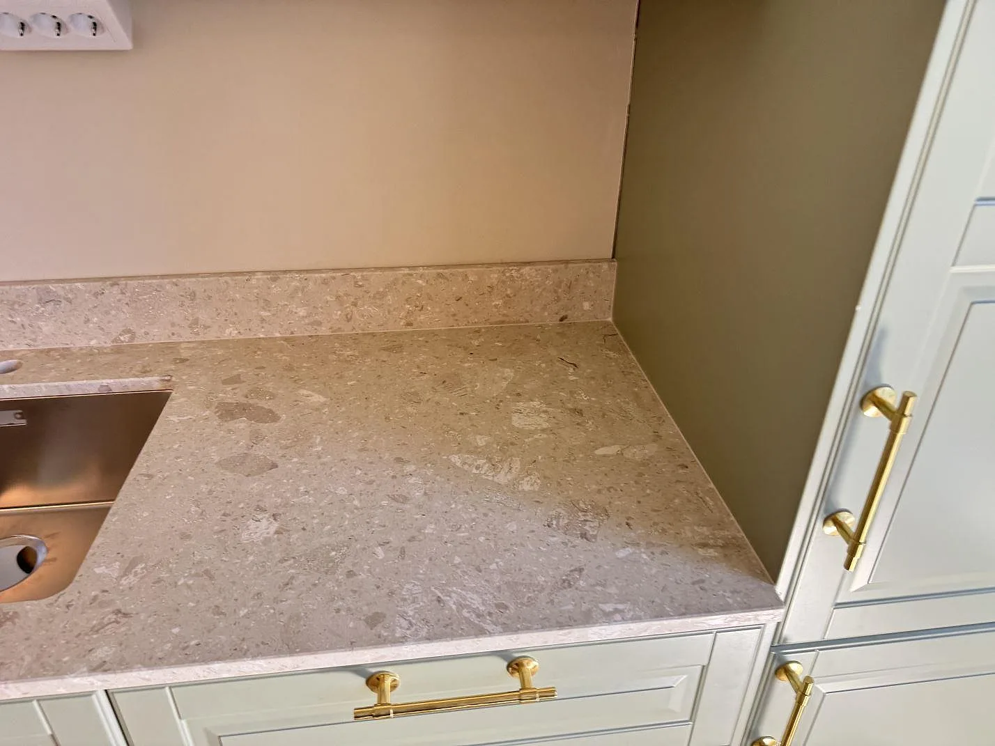 Køkkenbordplade i Terrazzo Perlato Royal, mat terrazzo, med rostfri vask, kort stänkkant og gröna köksluckor i Malmö.