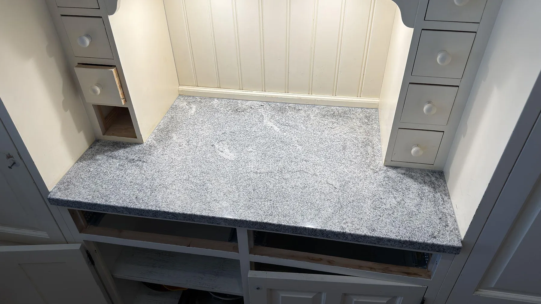 Poleret køkkenbordplade i graniten Viscont White, 30 mm, monteret mellan høje skåpsidor i ett køkken i Kista.