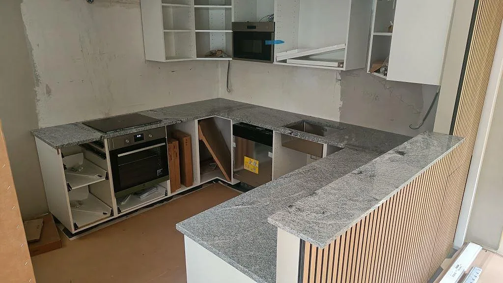 Køkkenbordplade i Viscont White granit, poleret, i ett U-format køkken med køkkenø og barhörna i Lund, fotograferat under montering.