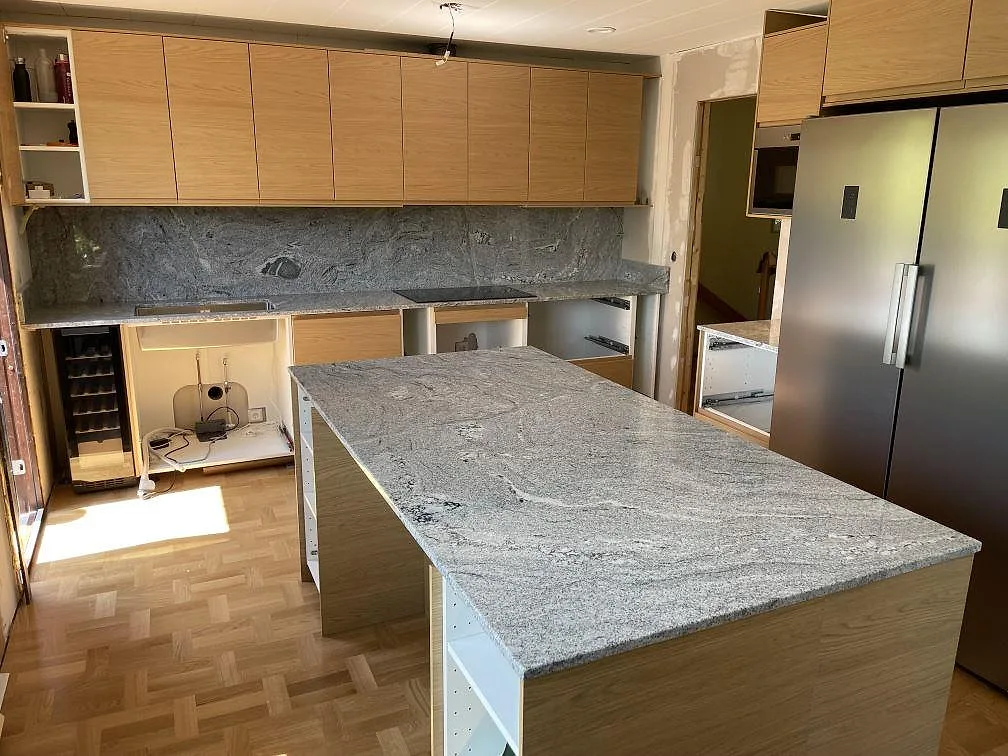 Køkken i Mariefred med poleret Viscont White granit på køkkenø, bakre Bordplade og stænkplade upp til överskåpen.